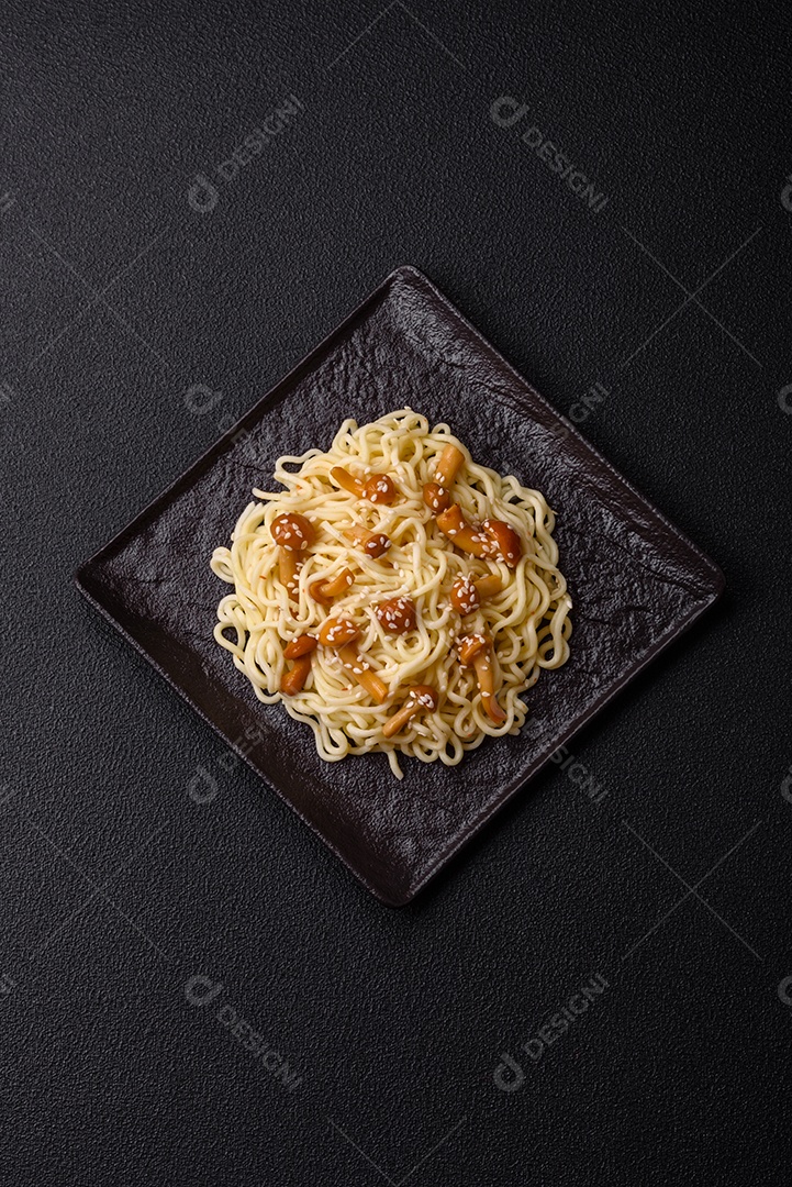Delicioso prato de cozinha asiática com macarrão de arroz, pimentão, cogumelos e especiarias sobre fundo escuro de concreto