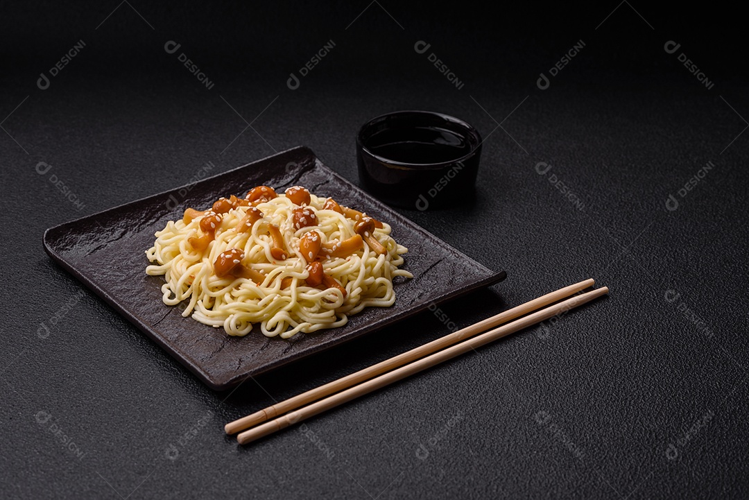 Delicioso prato de cozinha asiática com macarrão de arroz, pimentão, cogumelos e especiarias sobre fundo escuro de concreto