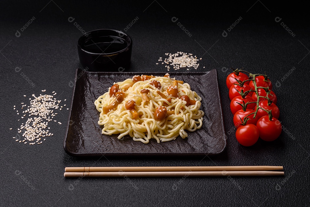 Delicioso prato de cozinha asiática com macarrão de arroz, pimentão, cogumelos e especiarias sobre fundo escuro de concreto
