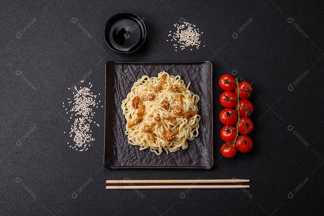 Delicioso prato de cozinha asiática com macarrão de arroz, pimentão, cogumelos e especiarias sobre fundo escuro de concreto