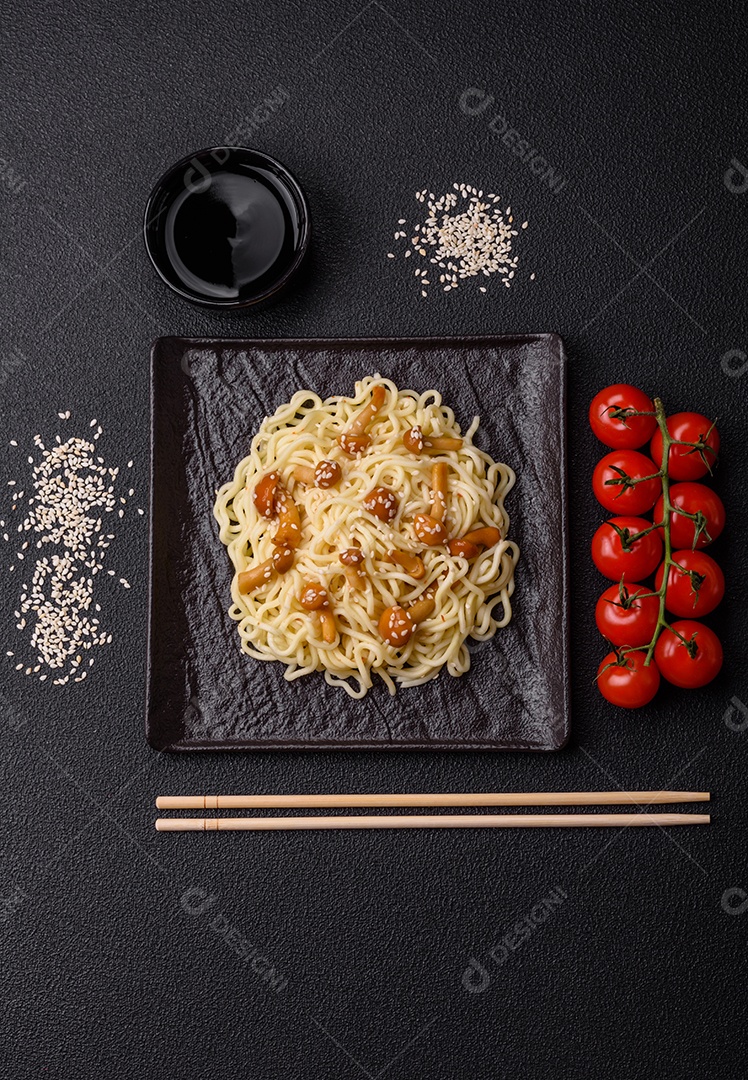 Delicioso prato de cozinha asiática com macarrão de arroz, pimentão, cogumelos e especiarias sobre fundo escuro de concreto