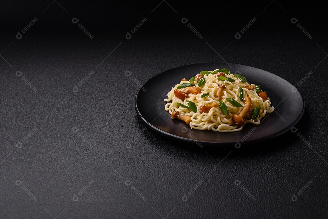 Delicioso prato de cozinha asiática com macarrão de arroz, pimentão, cogumelos e especiarias sobre fundo escuro de concreto