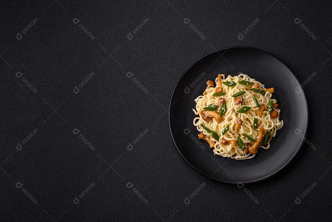 Delicioso prato de cozinha asiática com macarrão de arroz, pimentão, cogumelos e especiarias sobre fundo escuro de concreto