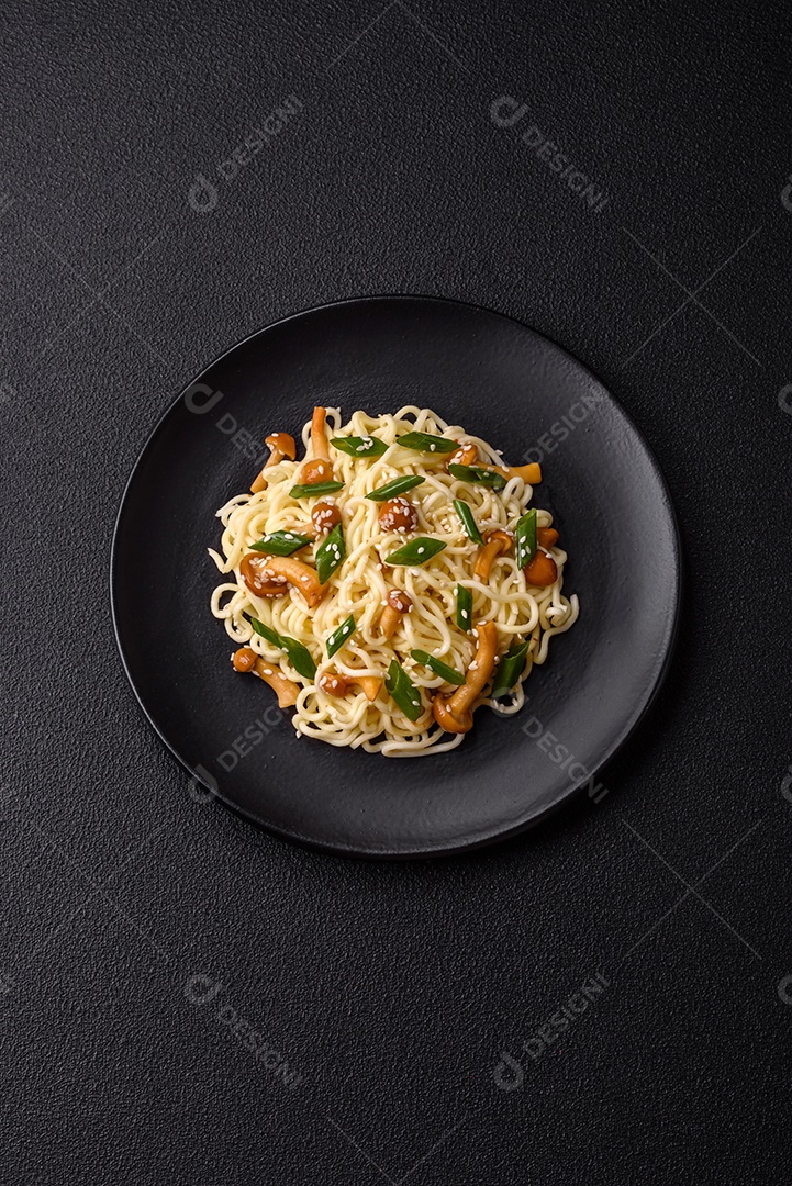 Delicioso prato de cozinha asiática com macarrão de arroz, pimentão, cogumelos e especiarias sobre fundo escuro de concreto