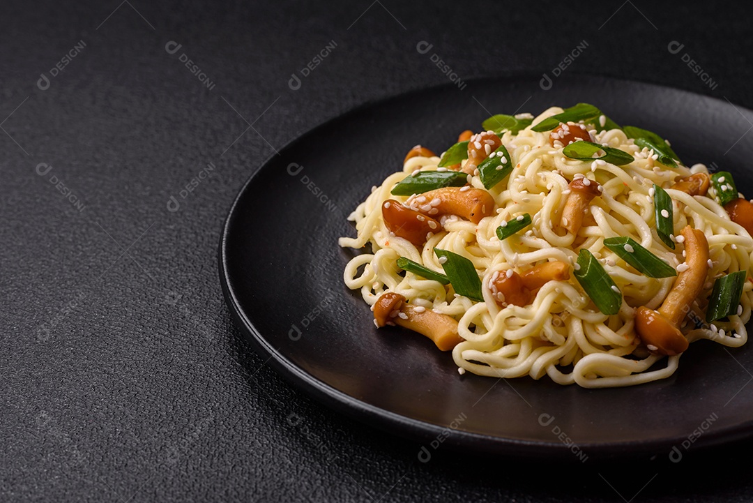 Delicioso prato de cozinha asiática com macarrão de arroz, pimentão, cogumelos e especiarias sobre fundo escuro de concreto