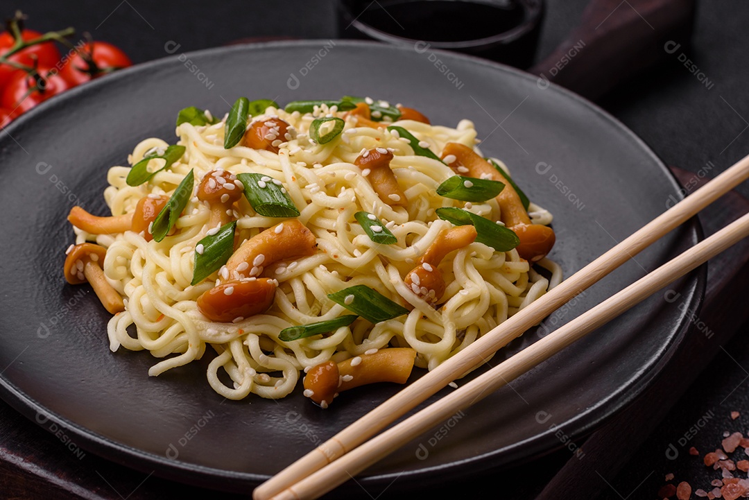 Delicioso prato de cozinha asiática com macarrão de arroz, pimentão, cogumelos e especiarias sobre fundo escuro de concreto