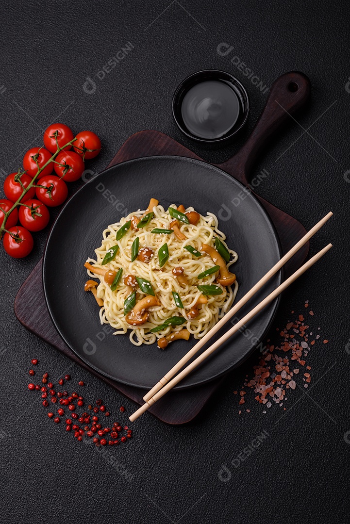 Delicioso prato de cozinha asiática com macarrão de arroz, pimentão, cogumelos e especiarias sobre fundo escuro de concreto
