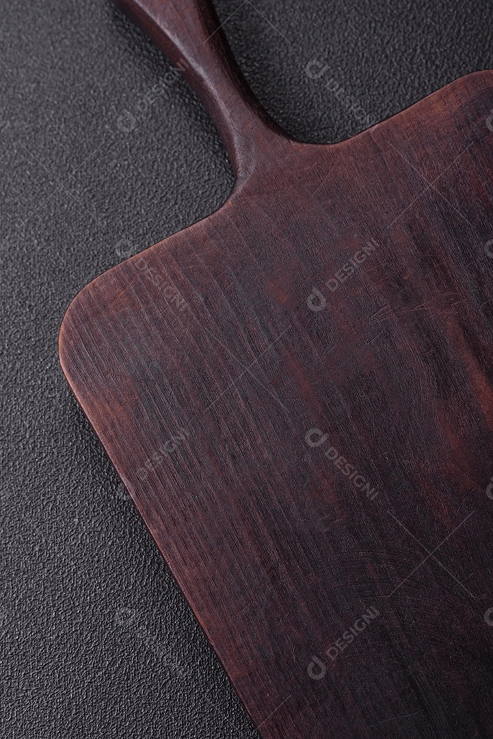 Tábua de corte de madeira vazia em fundo de concreto texturizado escuro. Talheres, preparação para o jantar