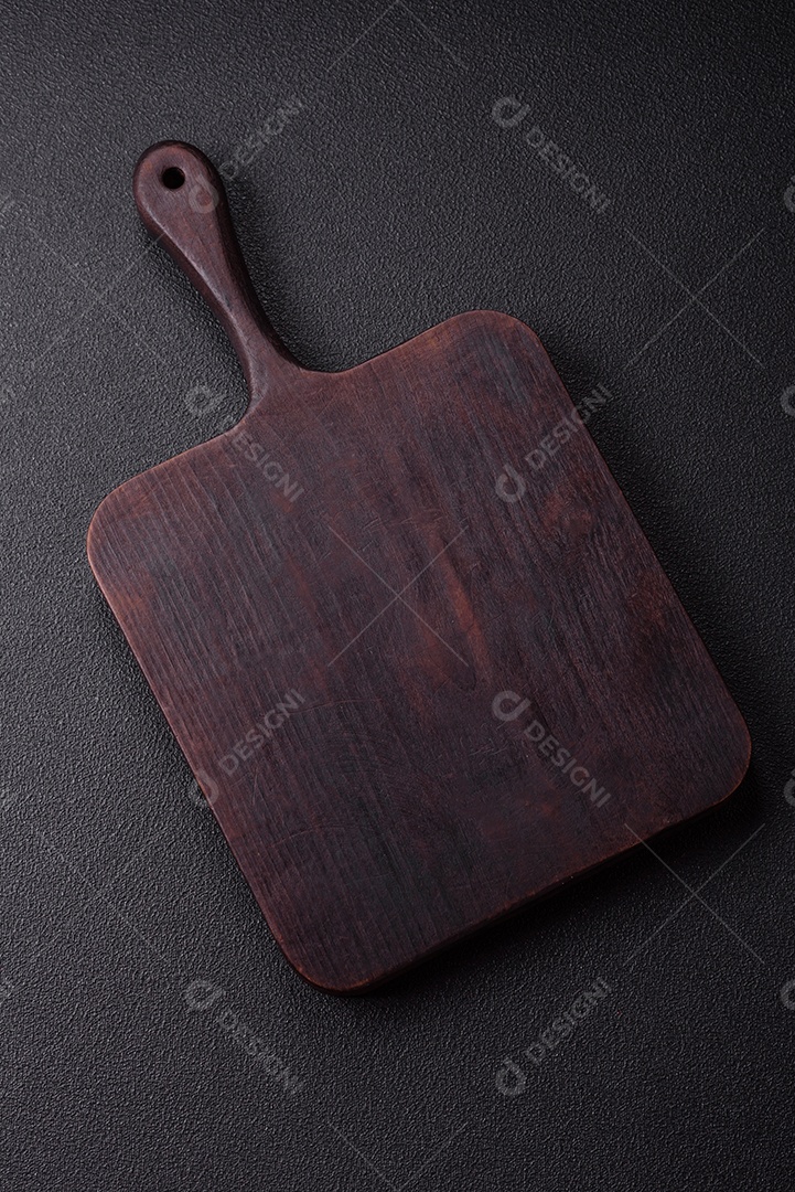 Tábua de madeira vazia com especiarias, sal e ervas em fundo escuro de concreto