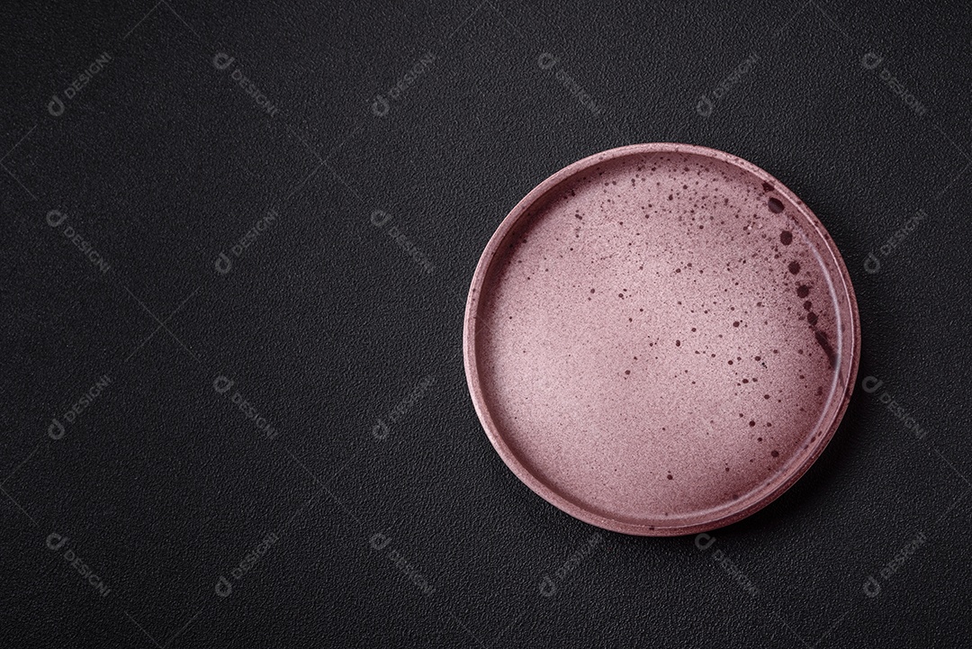 Placa redonda de cerâmica vazia em fundo de concreto texturizado escuro. Talheres, preparação para o jantar