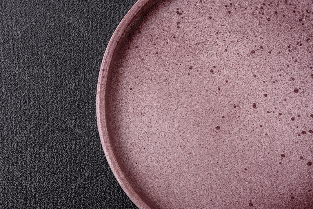 Placa redonda de cerâmica vazia em fundo de concreto texturizado escuro. Talheres, preparação para o jantar