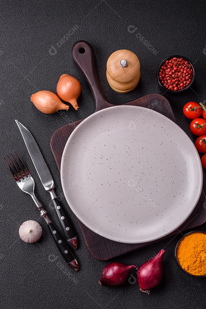 Placa redonda de cerâmica vazia em fundo de concreto texturizado escuro. Talheres, preparação para o jantar