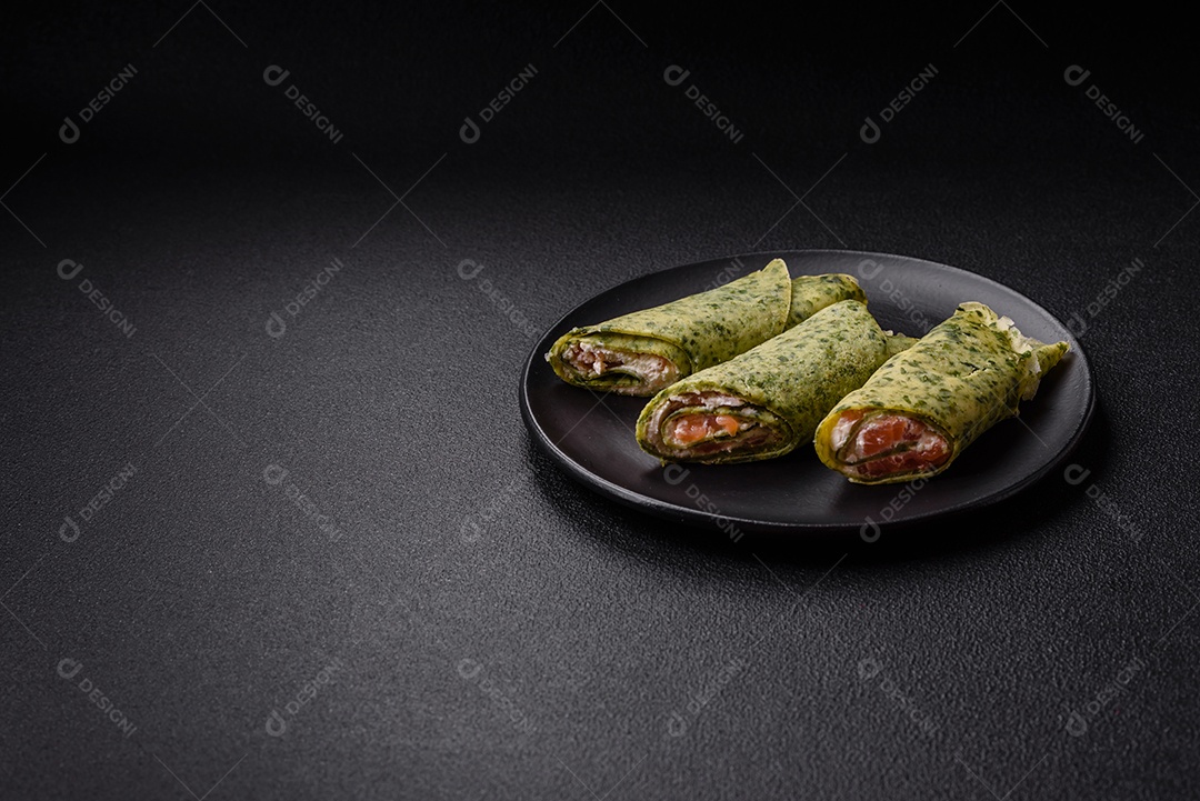 Deliciosas panquecas caseiras com espinafre, salmão, queijo Filadélfia com sal, especiarias e ervas sobre fundo escuro de concreto