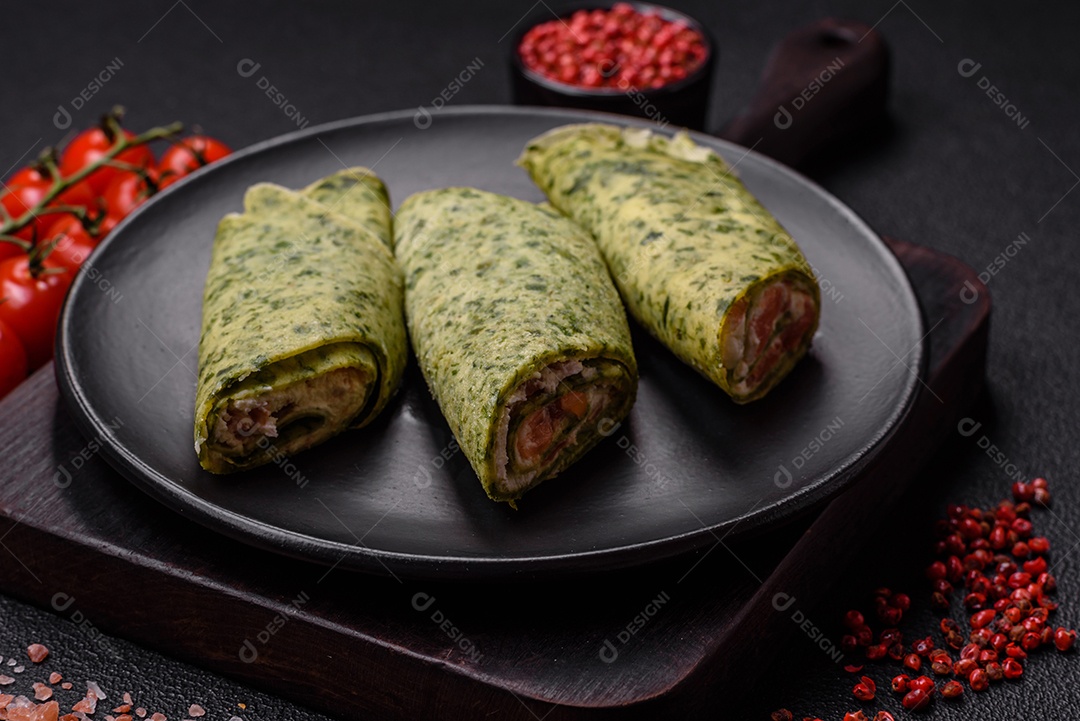 Deliciosas panquecas caseiras com espinafre, salmão, queijo Filadélfia com sal, especiarias e ervas sobre fundo escuro de concreto