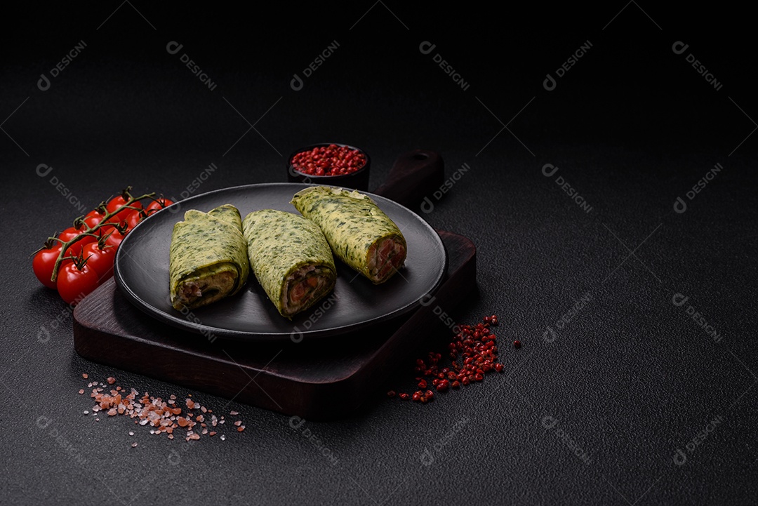 Deliciosas panquecas caseiras com espinafre, salmão, queijo Filadélfia com sal, especiarias e ervas sobre fundo escuro de concreto