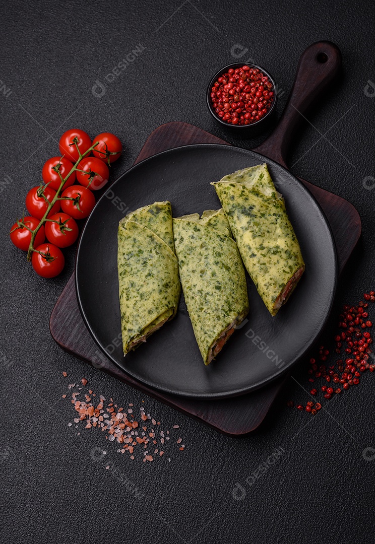 Deliciosas panquecas caseiras com espinafre, salmão, queijo Filadélfia com sal, especiarias e ervas sobre fundo escuro de concreto