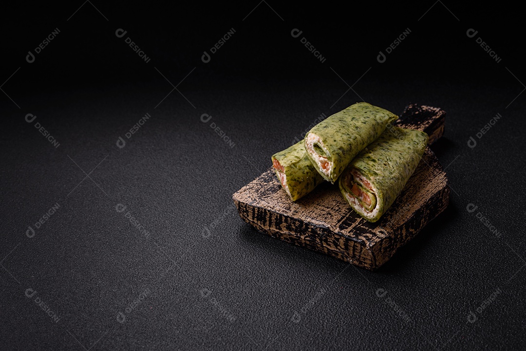 Deliciosas panquecas caseiras com espinafre, salmão, queijo Filadélfia com sal, especiarias e ervas sobre fundo escuro de concreto