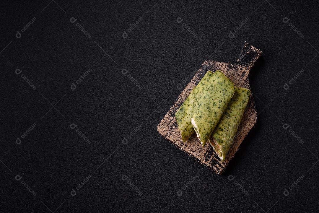 Deliciosas panquecas caseiras com espinafre, salmão, queijo Filadélfia com sal, especiarias e ervas sobre fundo escuro de concreto