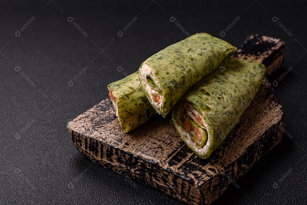 Deliciosas panquecas caseiras com espinafre, salmão, queijo Filadélfia com sal, especiarias e ervas sobre fundo escuro de concreto