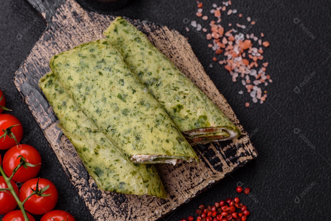 Deliciosas panquecas caseiras com espinafre, salmão, queijo Filadélfia com sal, especiarias e ervas sobre fundo escuro de concreto