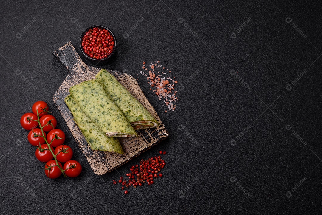 Deliciosas panquecas caseiras com espinafre, salmão, queijo Filadélfia com sal, especiarias e ervas sobre fundo escuro de concreto