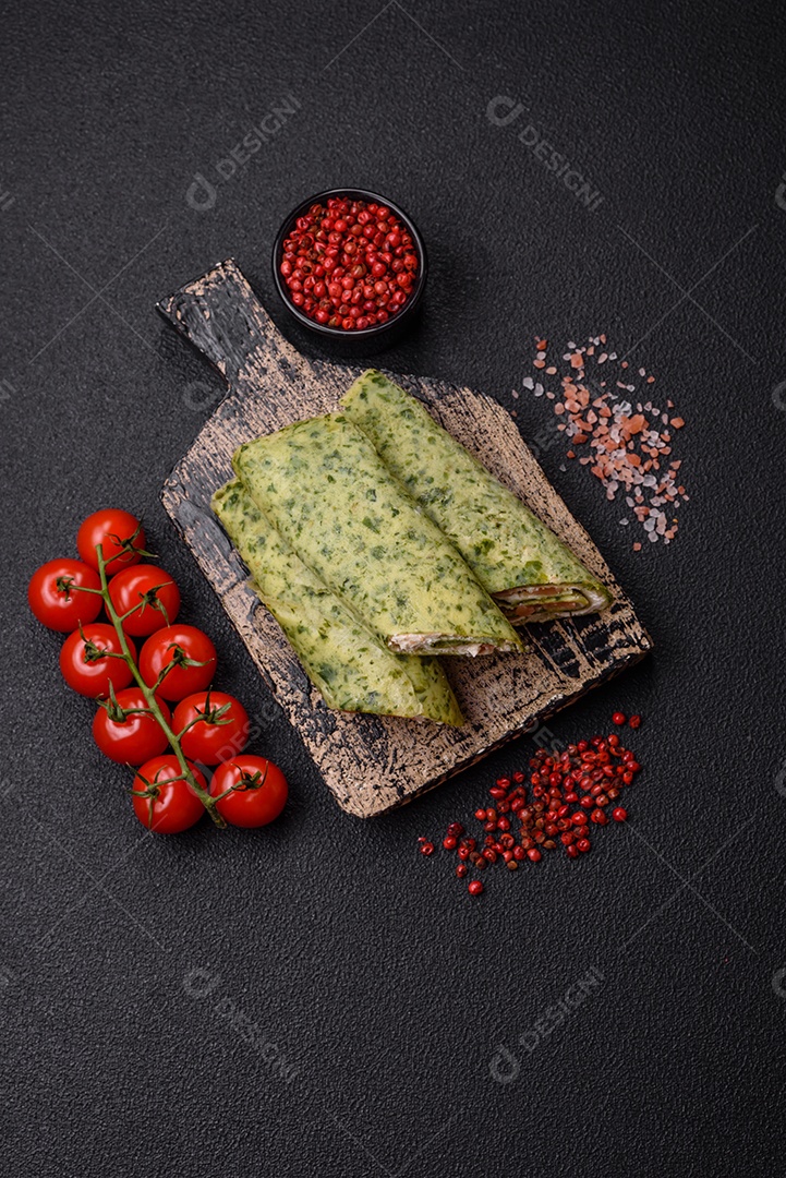 Deliciosas panquecas caseiras com espinafre, salmão, queijo Filadélfia com sal, especiarias e ervas sobre fundo escuro de concreto