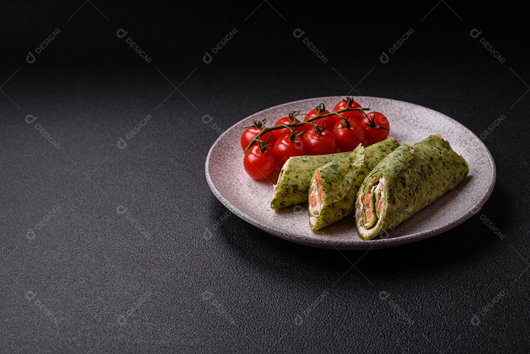 Deliciosas panquecas caseiras com espinafre, salmão, queijo Filadélfia com sal, especiarias e ervas sobre fundo escuro de concreto