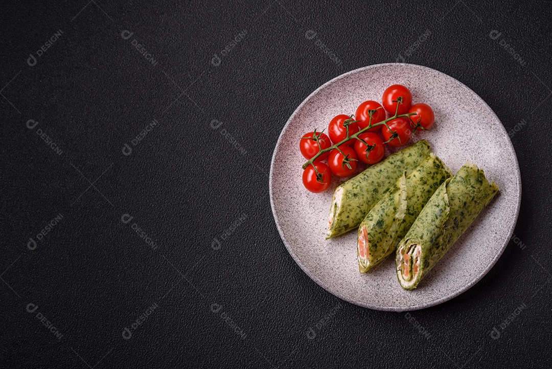 Deliciosas panquecas caseiras com espinafre, salmão, queijo Filadélfia com sal, especiarias e ervas sobre fundo escuro de concreto
