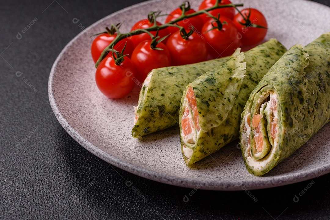 Deliciosas panquecas caseiras com espinafre, salmão, queijo Filadélfia com sal, especiarias e ervas sobre fundo escuro de concreto