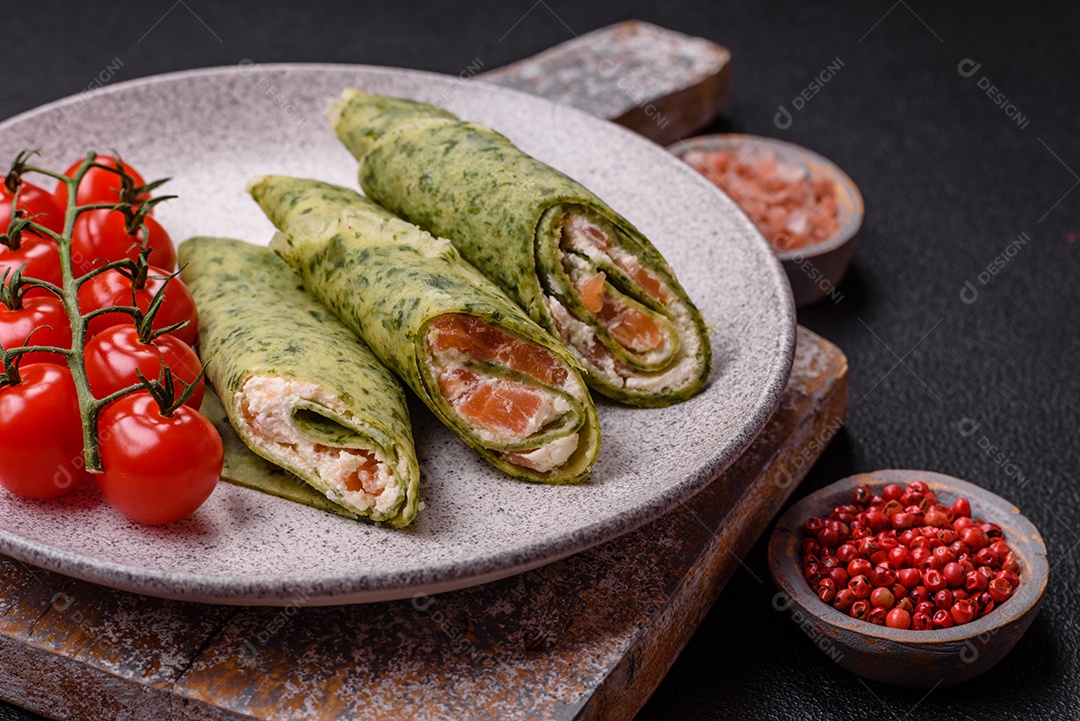 Deliciosas panquecas caseiras com espinafre, salmão, queijo Filadélfia com sal, especiarias e ervas sobre fundo escuro de concreto