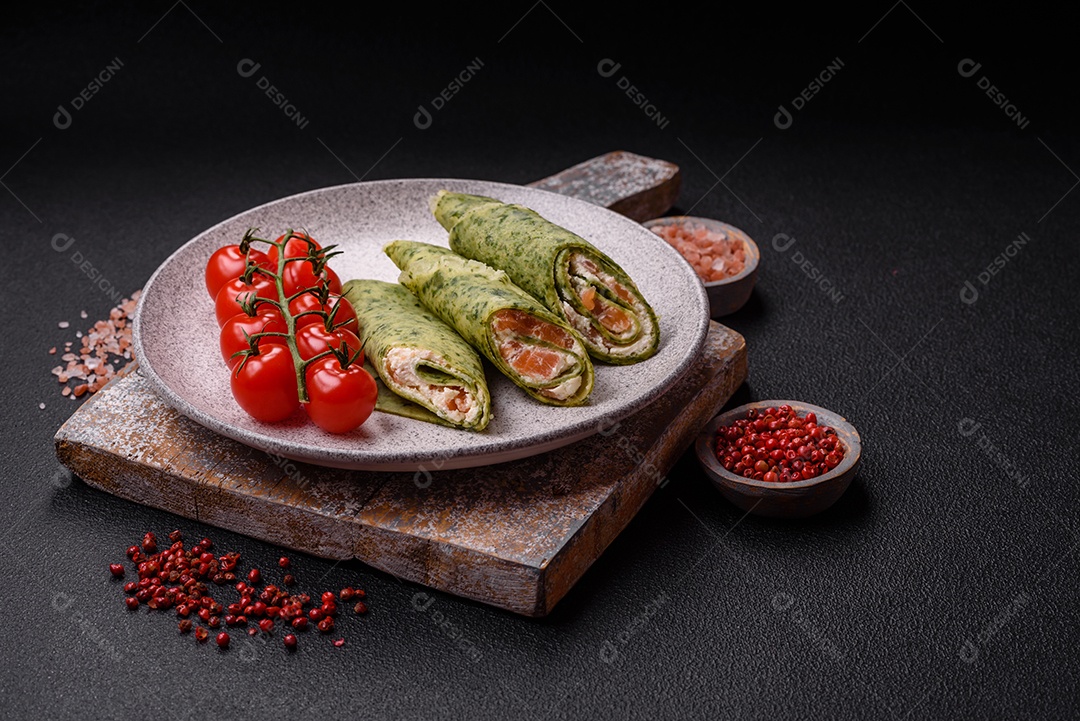 Deliciosas panquecas caseiras com espinafre, salmão, queijo Filadélfia com sal, especiarias e ervas sobre fundo escuro de concreto