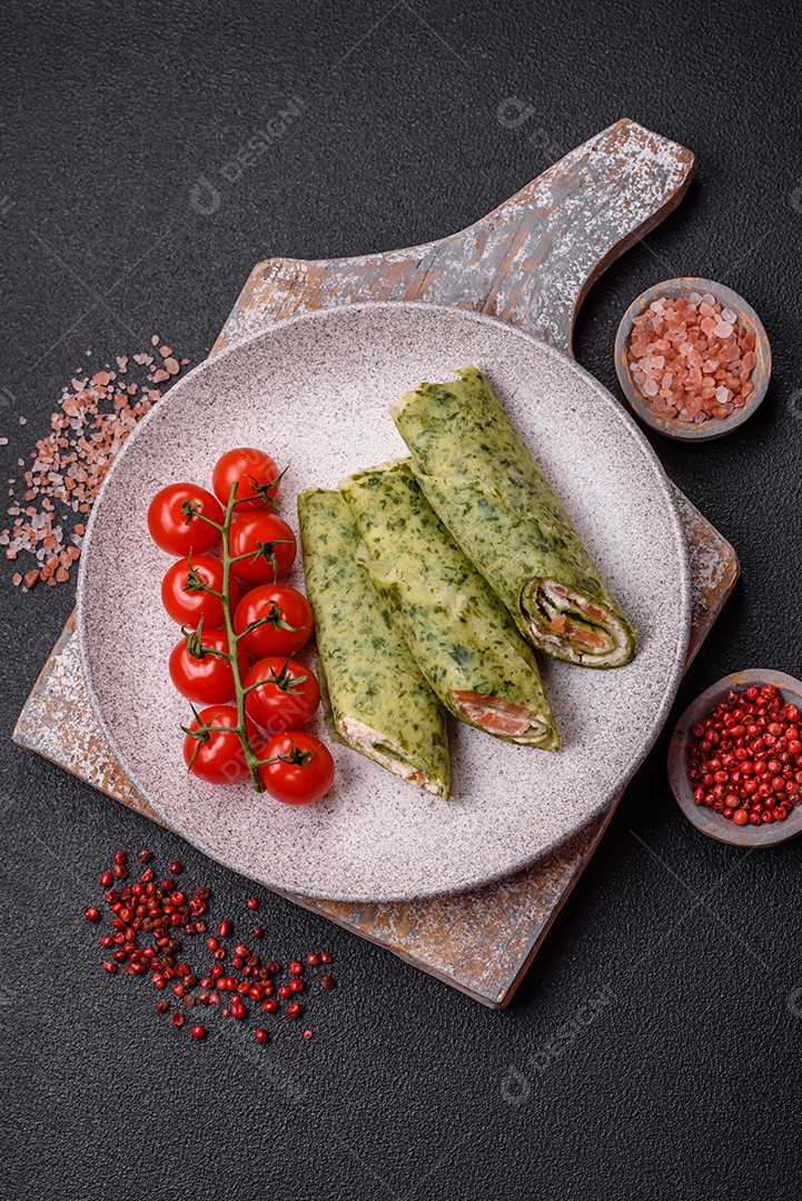 Deliciosas panquecas caseiras com espinafre, salmão, queijo Filadélfia com sal, especiarias e ervas sobre fundo escuro de concreto