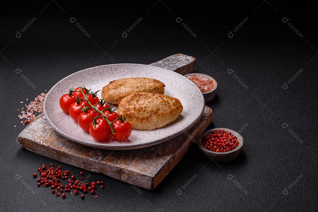 Deliciosas costeletas picadas fritas frescas com especiarias e ervas sobre um fundo escuro de concreto