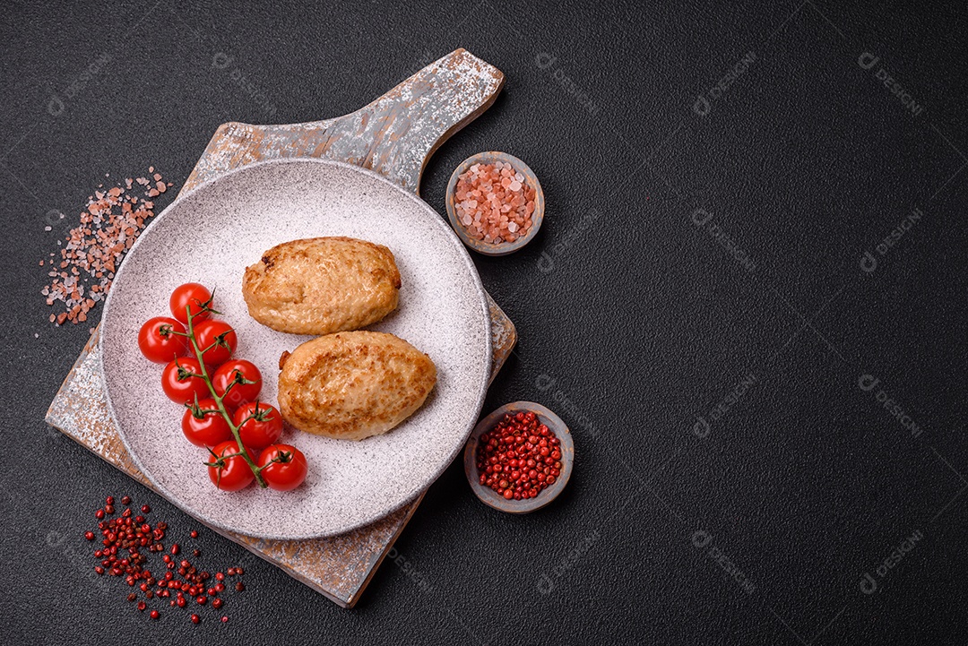 Deliciosas costeletas picadas fritas frescas com especiarias e ervas sobre um fundo escuro de concreto