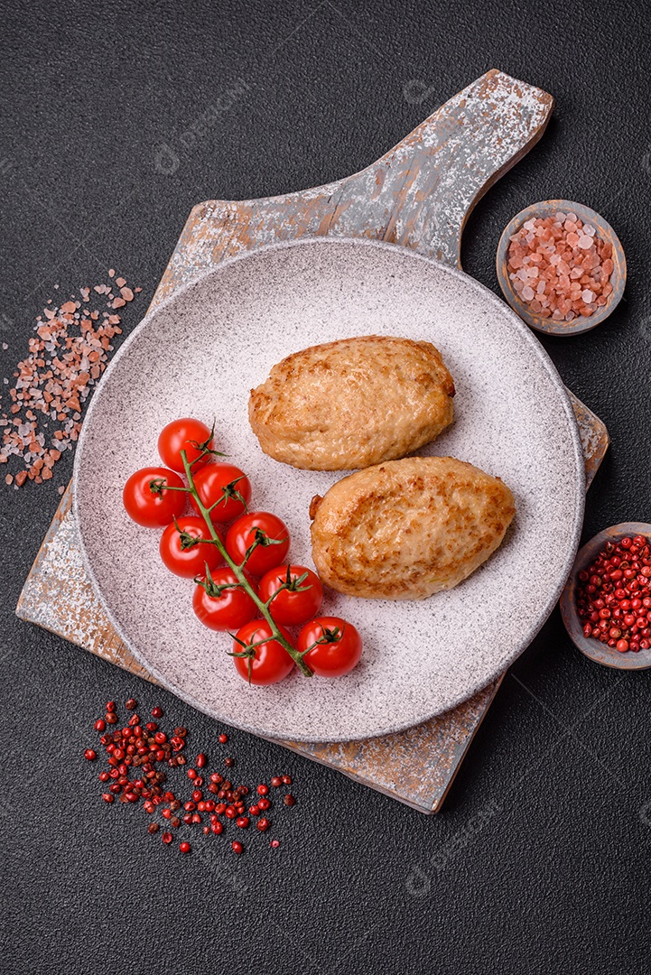 Deliciosas costeletas picadas fritas frescas com especiarias e ervas sobre um fundo escuro de concreto
