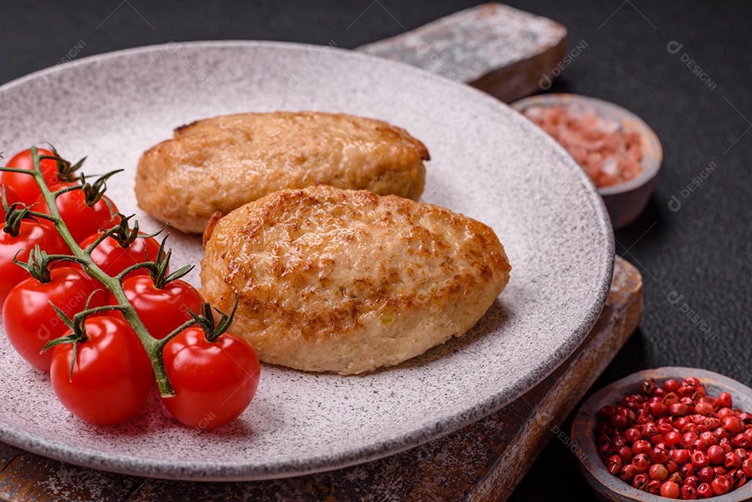 Deliciosas costeletas picadas fritas frescas com especiarias e ervas sobre um fundo escuro de concreto