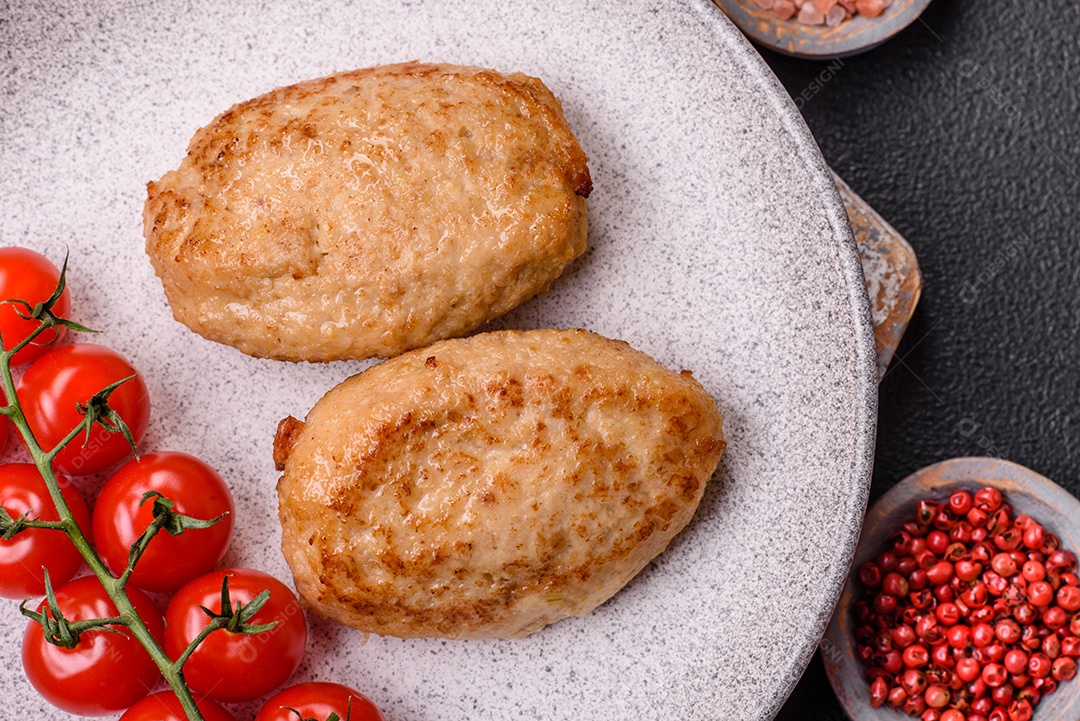 Deliciosas costeletas picadas fritas frescas com especiarias e ervas sobre um fundo escuro de concreto