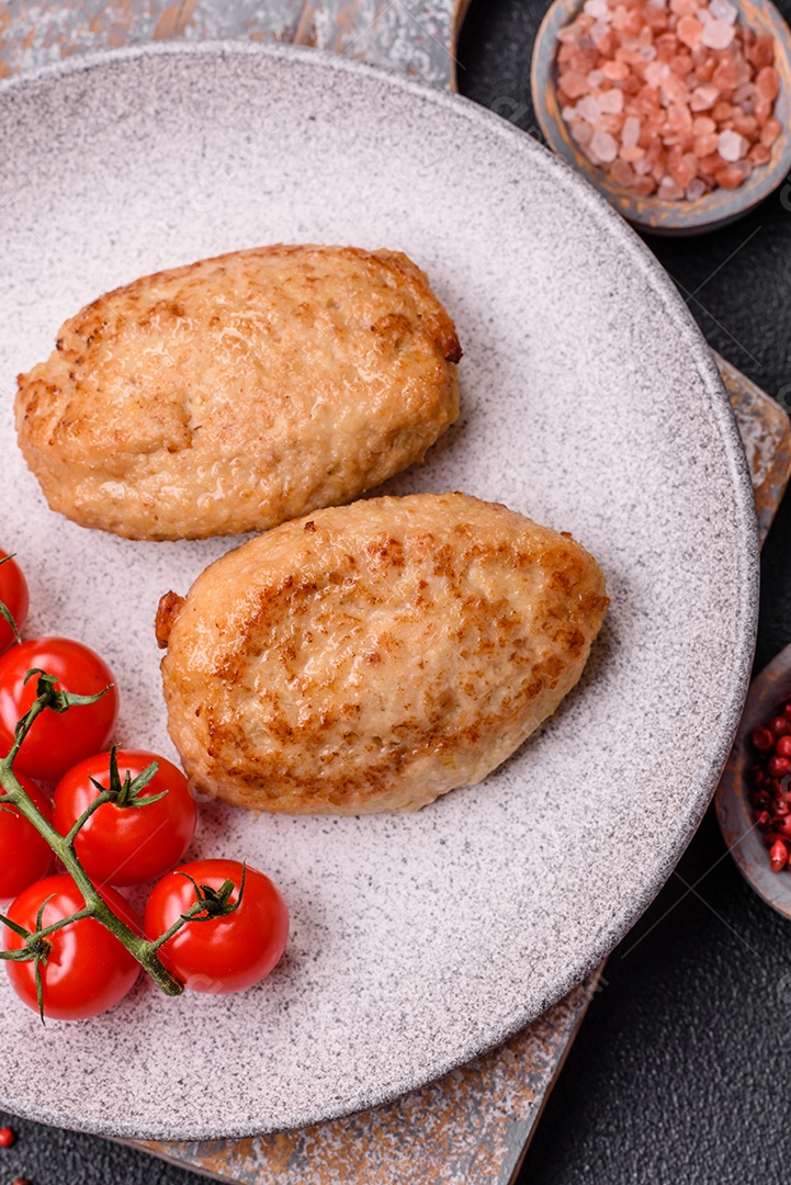 Deliciosas costeletas picadas fritas frescas com especiarias e ervas sobre um fundo escuro de concreto