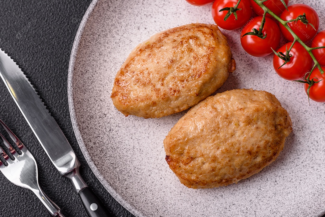 Deliciosas costeletas picadas fritas frescas com especiarias e ervas sobre um fundo escuro de concreto