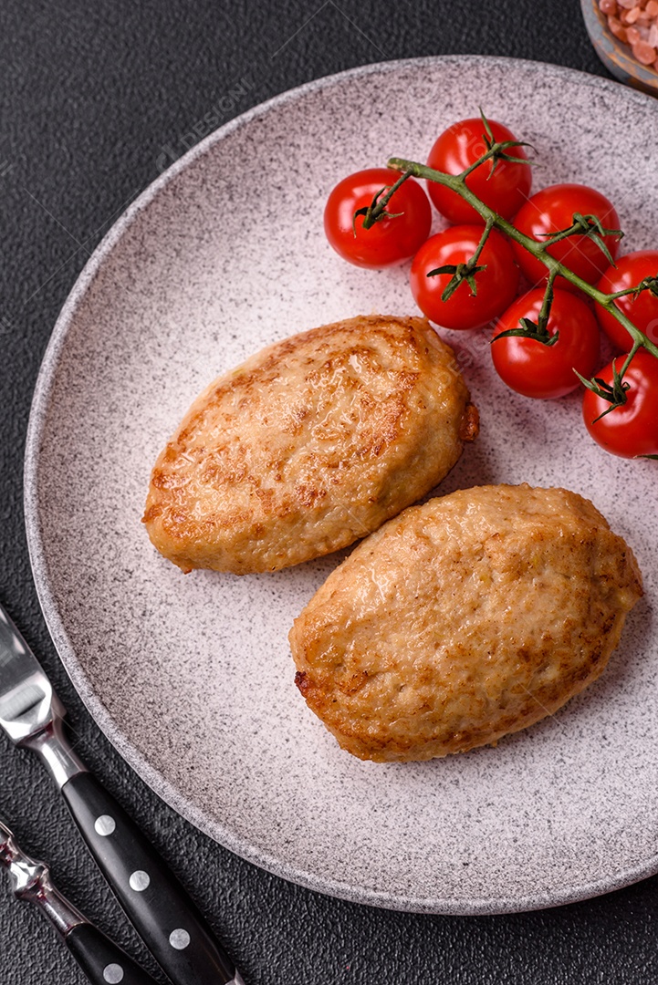 Deliciosas costeletas picadas fritas frescas com especiarias e ervas sobre um fundo escuro de concreto