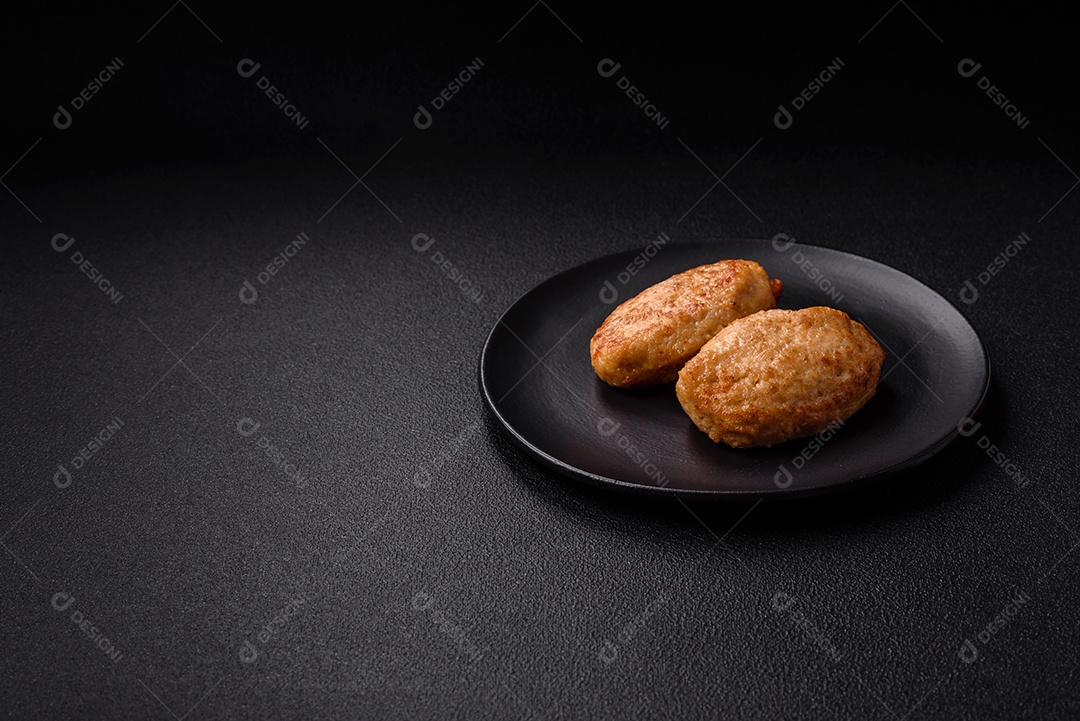 Deliciosas costeletas picadas fritas frescas com especiarias e ervas sobre um fundo escuro de concreto