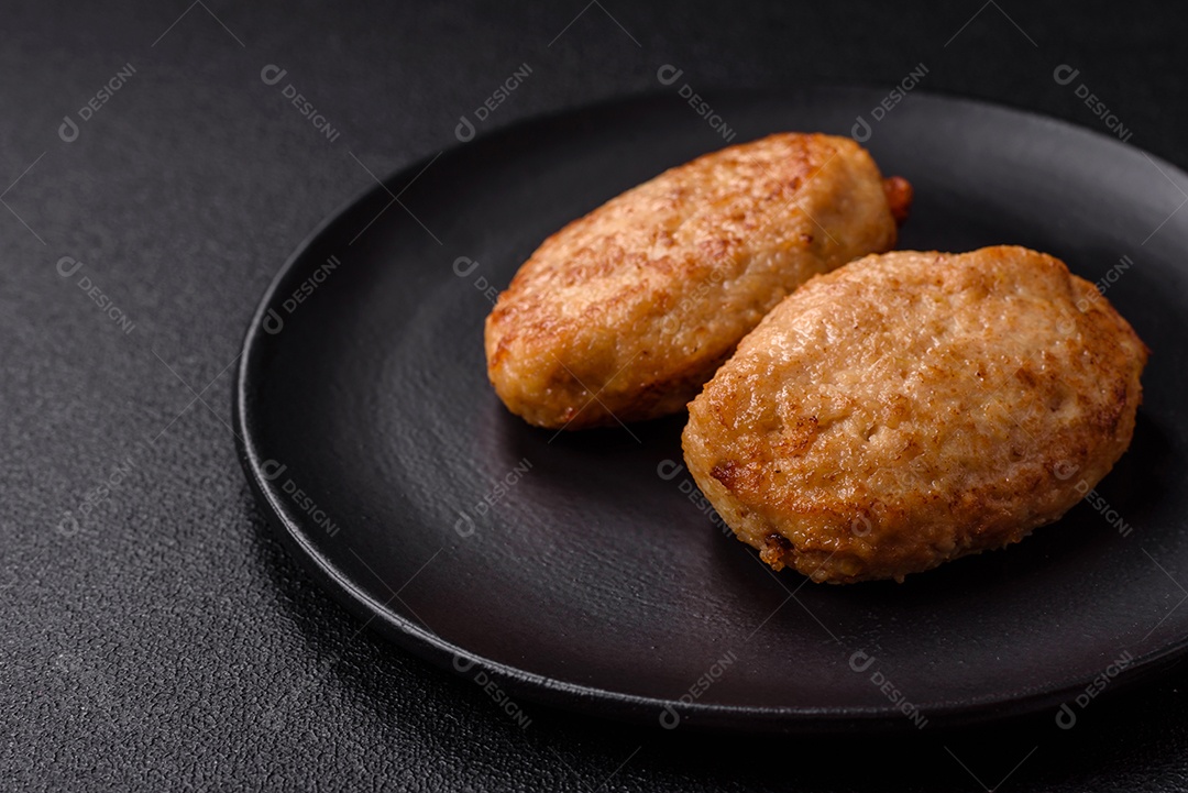 Deliciosas costeletas picadas fritas frescas com especiarias e ervas sobre um fundo escuro de concreto