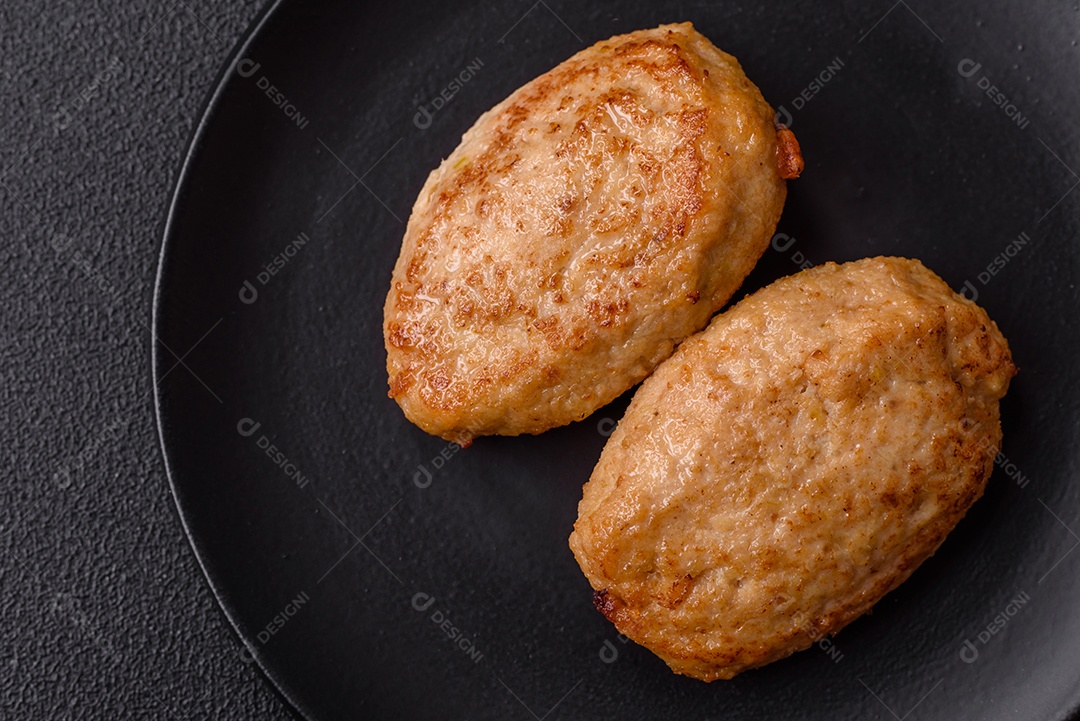 Deliciosas costeletas picadas fritas frescas com especiarias e ervas sobre um fundo escuro de concreto