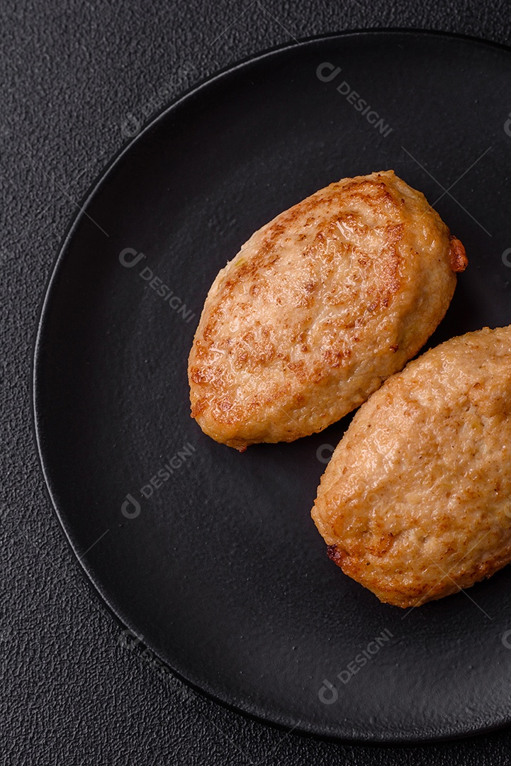 Deliciosas costeletas picadas fritas frescas com especiarias e ervas sobre um fundo escuro de concreto