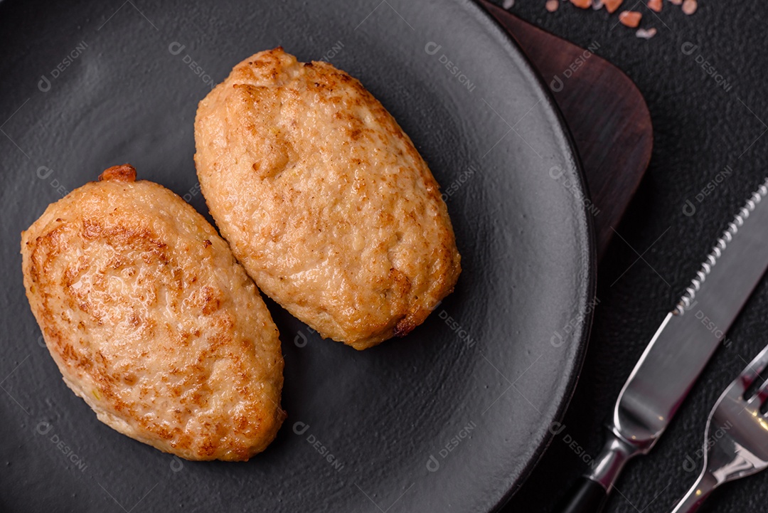 Deliciosas costeletas picadas fritas frescas com especiarias e ervas sobre um fundo escuro de concreto
