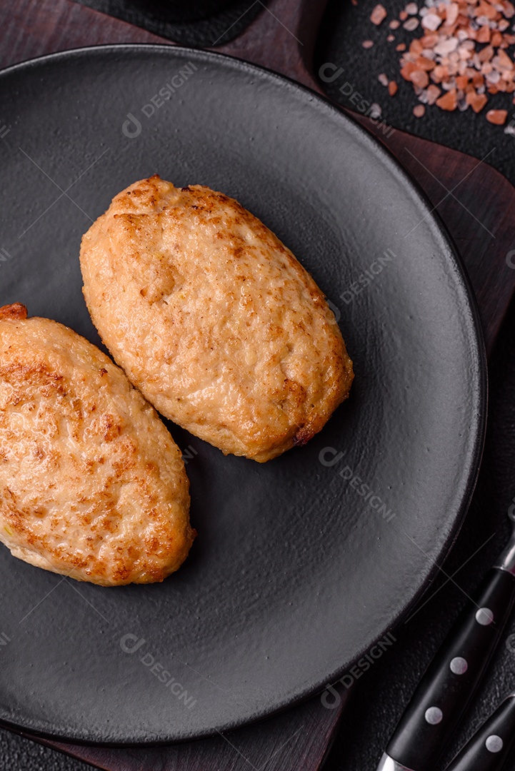 Deliciosas costeletas picadas fritas frescas com especiarias e ervas sobre um fundo escuro de concreto