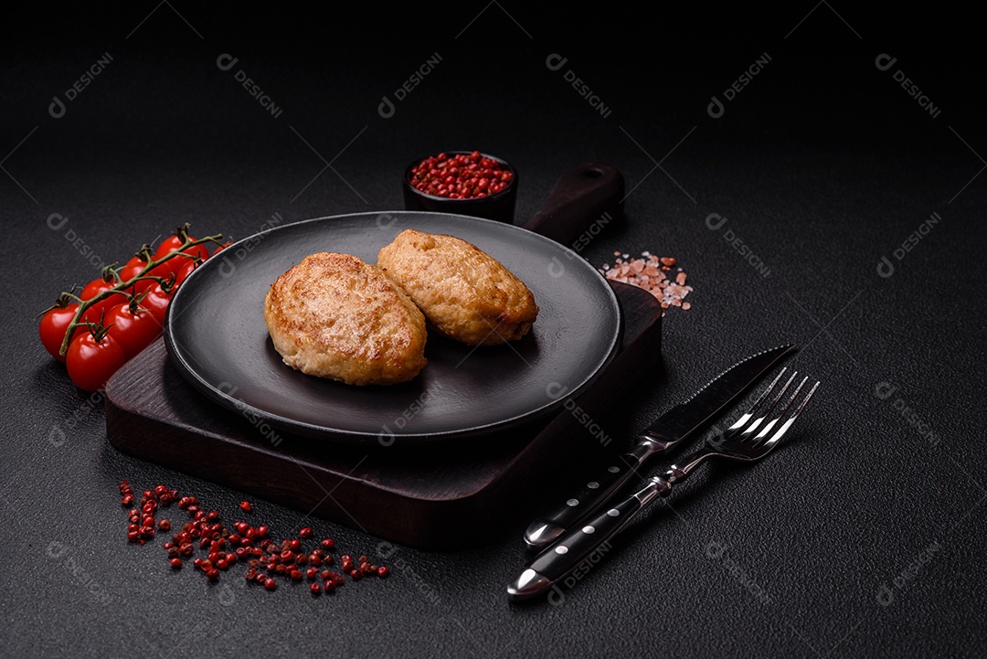 Deliciosas costeletas picadas fritas frescas com especiarias e ervas sobre um fundo escuro de concreto