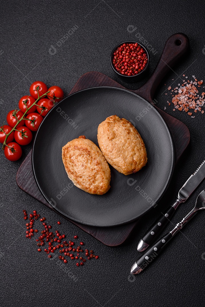 Deliciosas costeletas picadas fritas frescas com especiarias e ervas sobre um fundo escuro de concreto