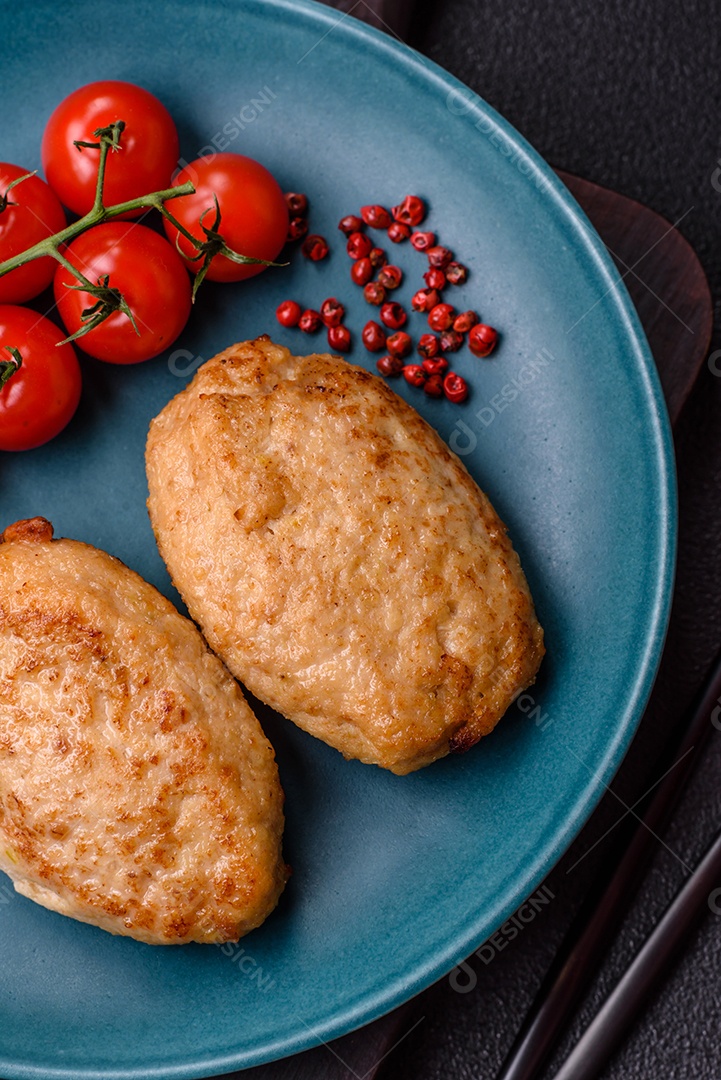 Deliciosas costeletas picadas fritas frescas com especiarias e ervas sobre um fundo escuro de concreto