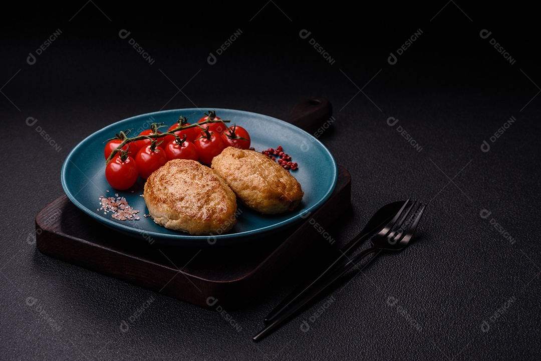 Deliciosas costeletas picadas fritas frescas com especiarias e ervas sobre um fundo escuro de concreto